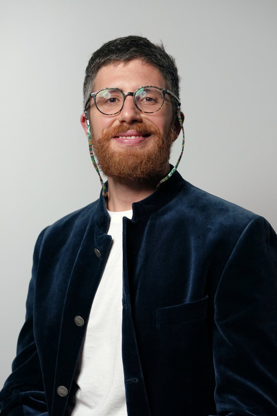 Ritratto in studio di Andrea Parrella, sorridente, con giacca di velluto blu