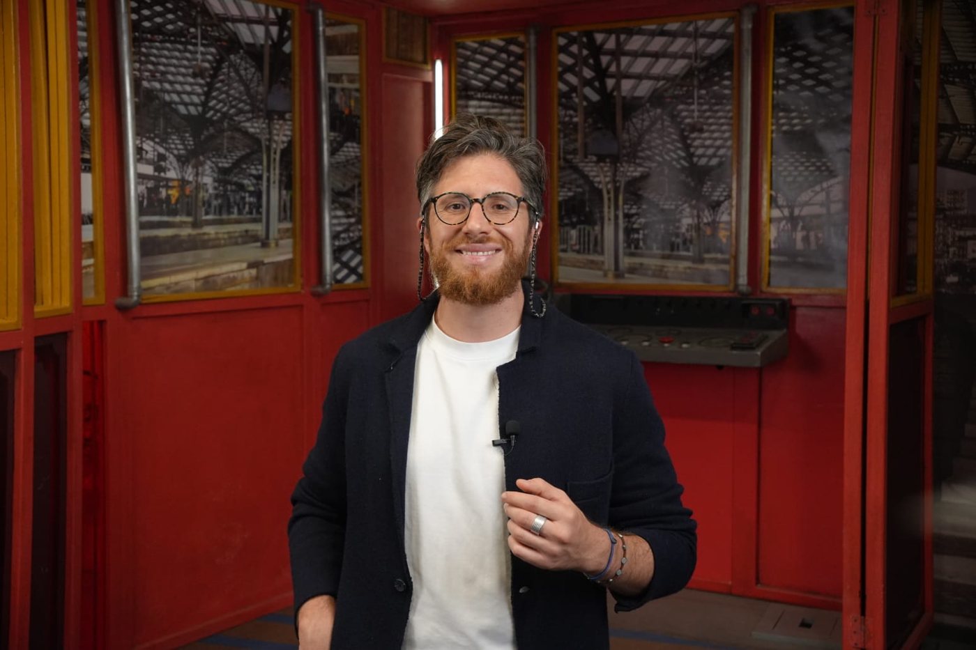 Andrea Parrella sorridente in un set dalle pareti rosse